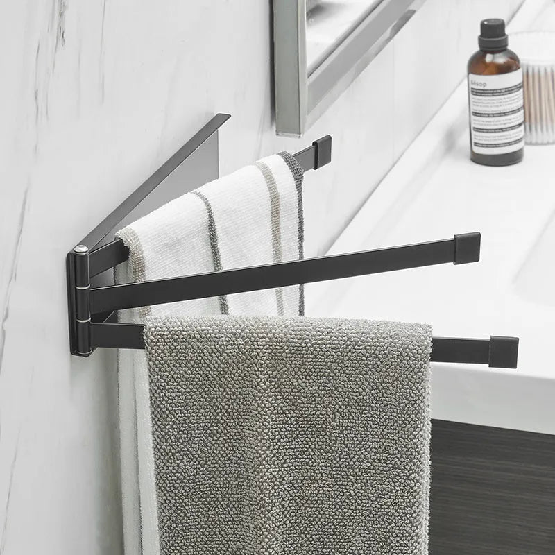 Black folding towel rack mounted on bathroom wall with towel hanging