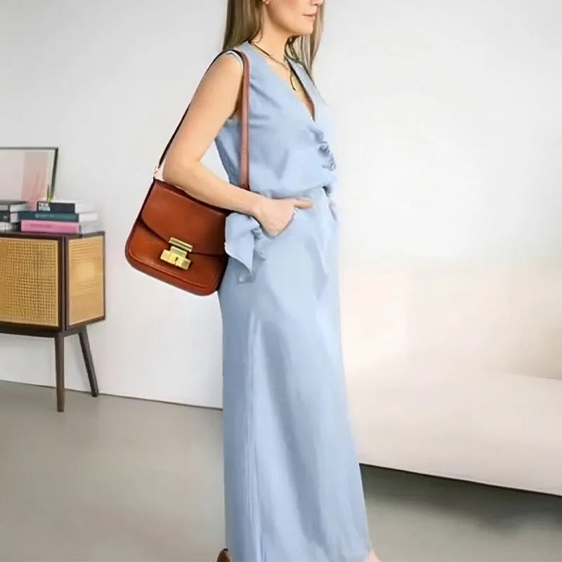 A woman wearing a blue sleeveless top and matching long skirt from a casual two-piece suit set.