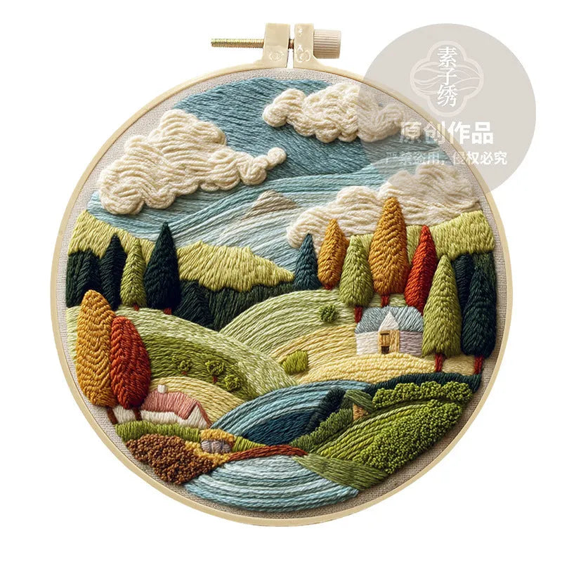 Embroidery DIY kit with cotton landscape fabric, bamboo frame, needles, and thread on wooden table