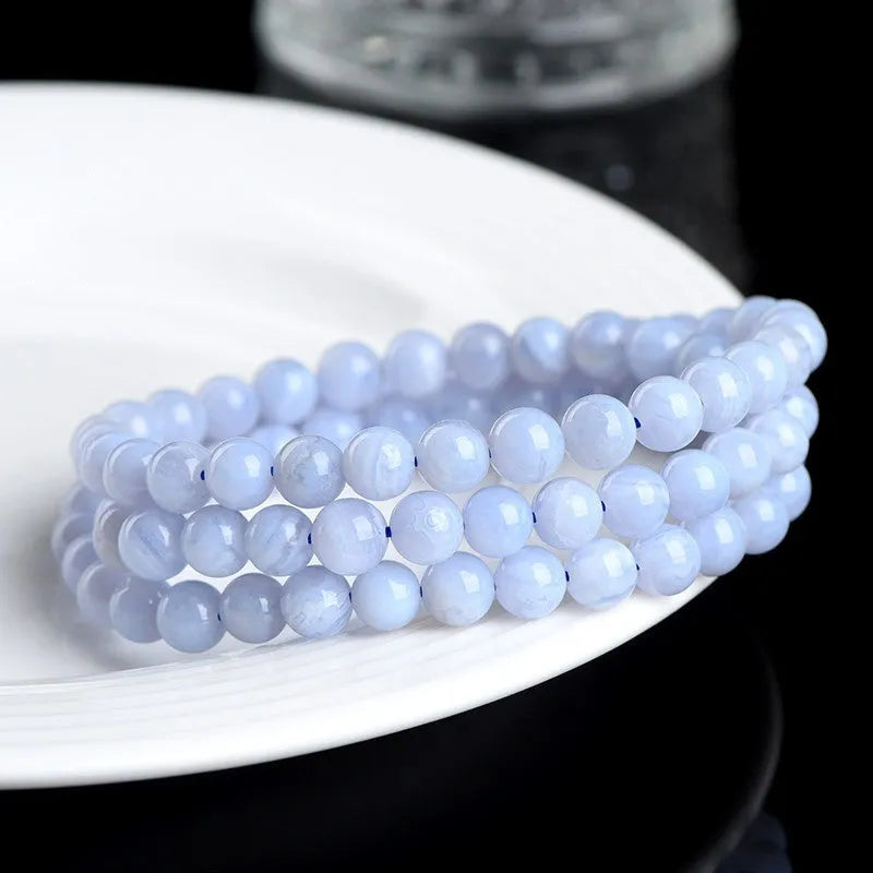 Blue agate bead bracelet with striped pattern and ruyi design on a white background.