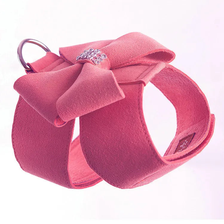 A pink microfiber puppy chest strap harness with a large central bowknot, showing adjustable buckles.