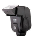 Compact silver hot shoe camera flash with head tilted upwards, shown next to two AA batteries for scale.