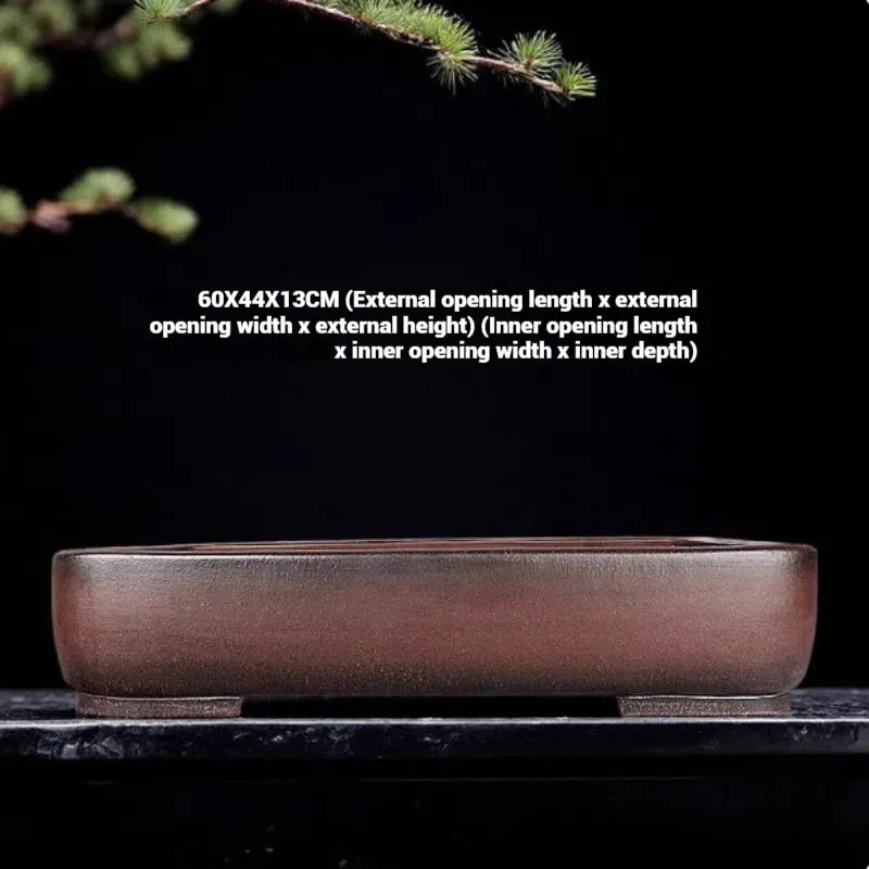 Handmade antique rectangular purple clay flower pot on a wooden surface.