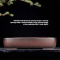 Handmade antique rectangular purple clay flower pot on a wooden surface.