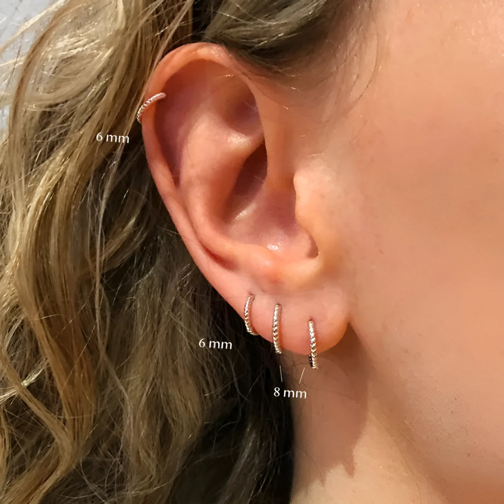 Close-up of a pair of twisted string round sterling silver ring earrings on a flat surface.