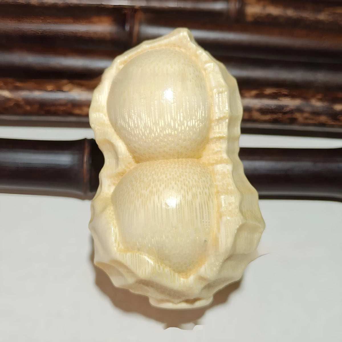 Solid natural bamboo carving peanut ornament on a neutral background