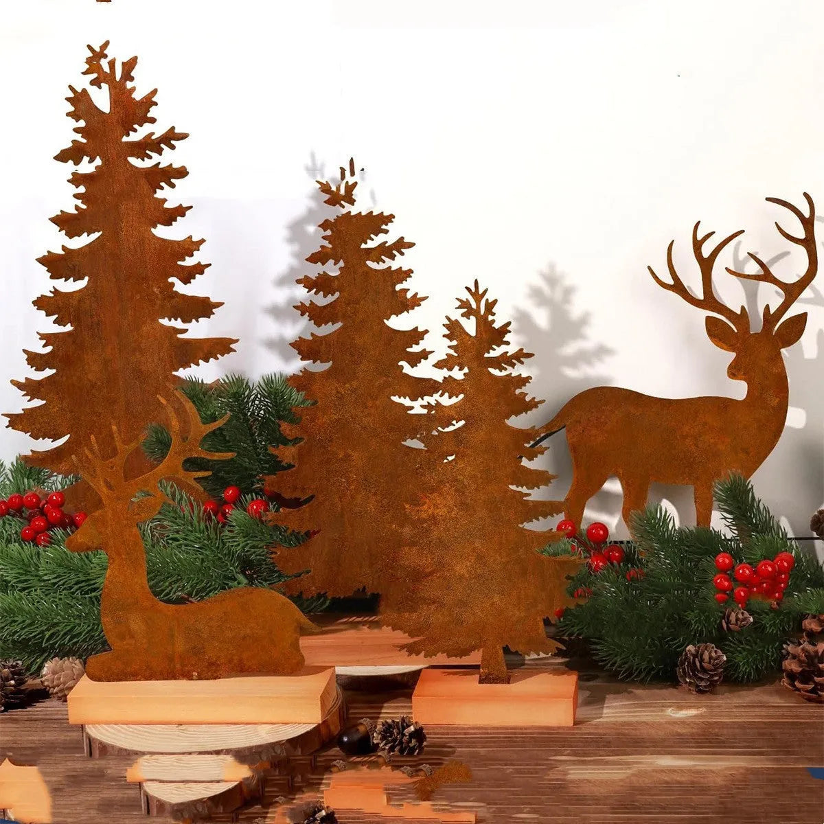 Three rusty metal Christmas decorations featuring elk and trees on a wooden surface