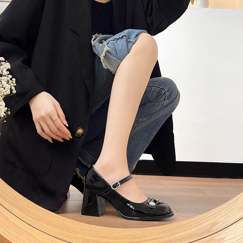 Women's black patent leather chunky heel shoes with round toe and buckle strap.