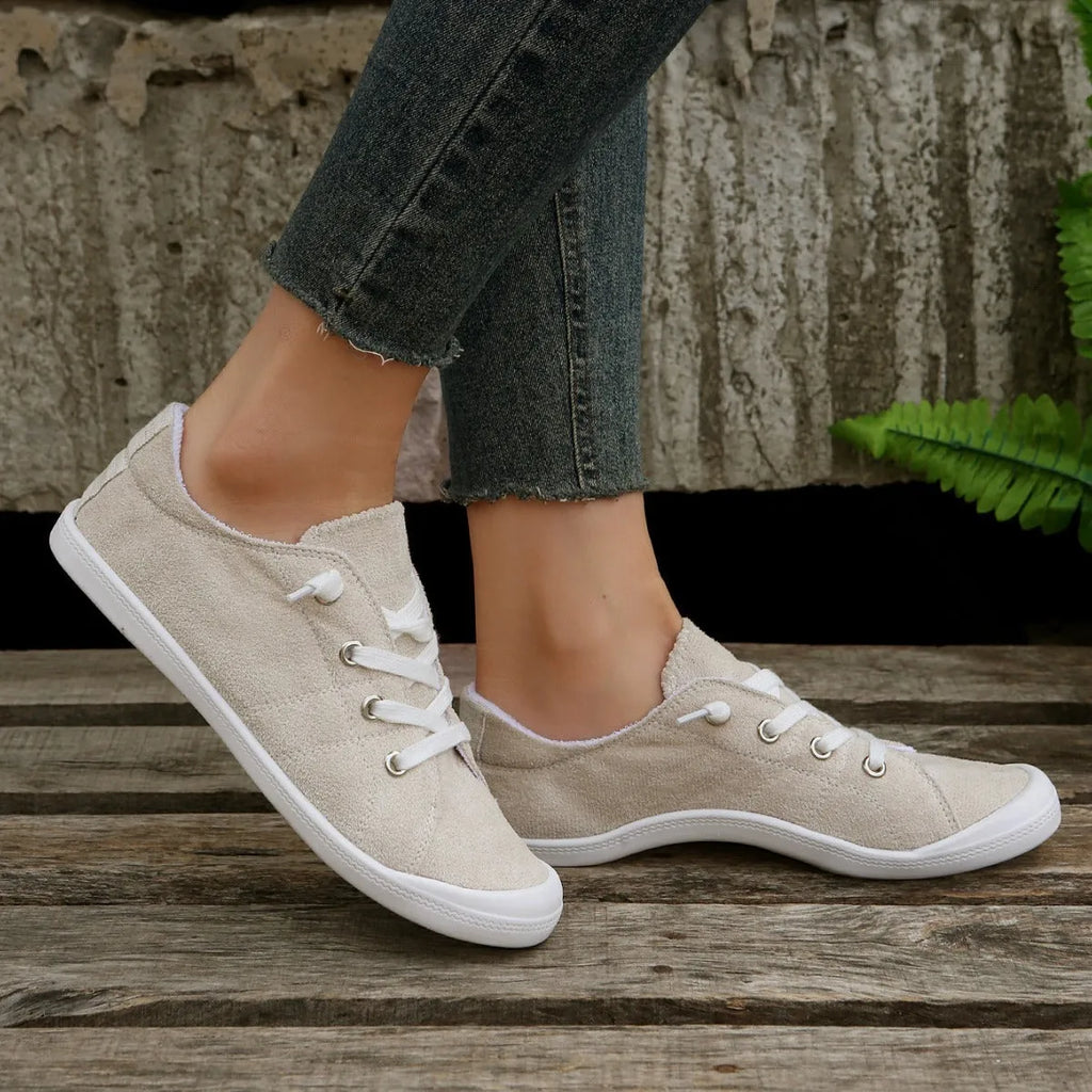 Women's creamy-white low-top fabric sneaker with rubber sole shown from side view