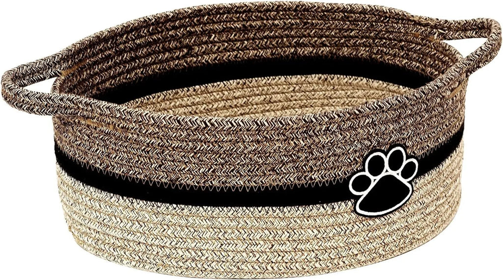 Small light beige handwoven cotton rope storage basket with wooden handle on a wooden table.