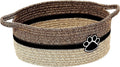 Small light beige handwoven cotton rope storage basket with wooden handle on a wooden table.