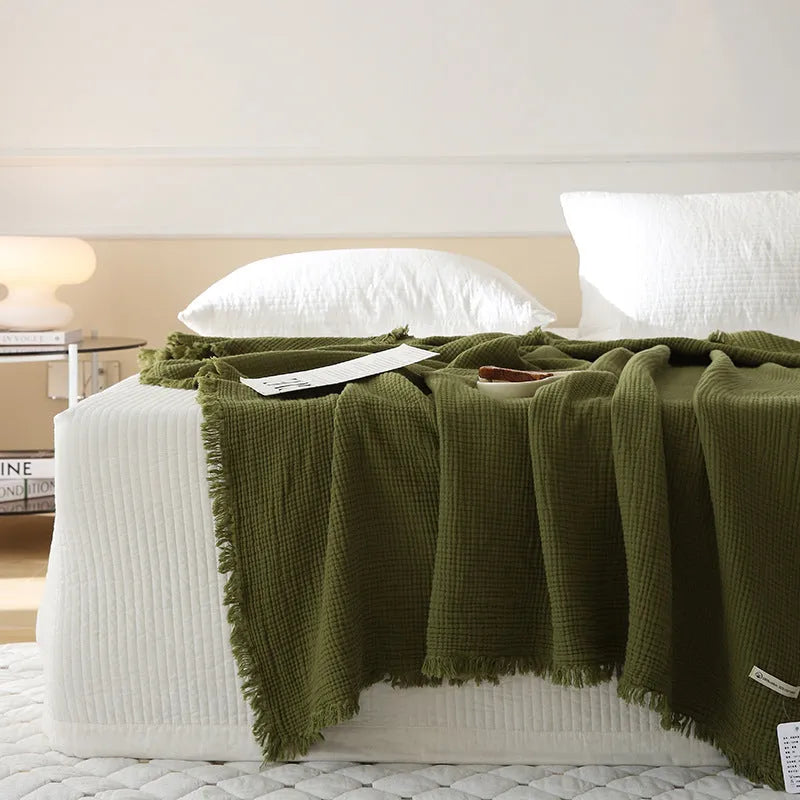 Four-layer cotton gauze tassel blanket in avocado green colour showing tassel detailing