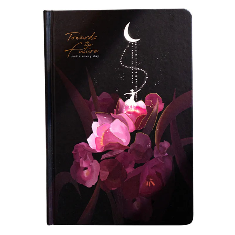 A5 notebook with a luminous cover open to show pages with colour illustrations, in deep blue, gold, light blue, or purple.