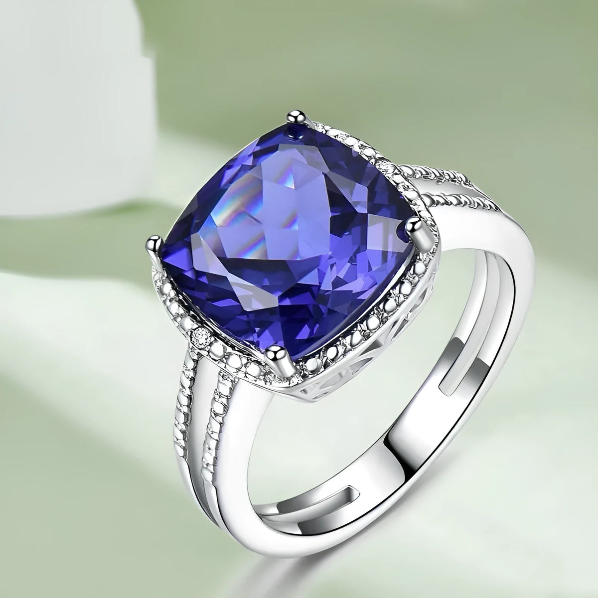 Blue tanzanite gemstone set in a sterling silver women's ring on a grey background.