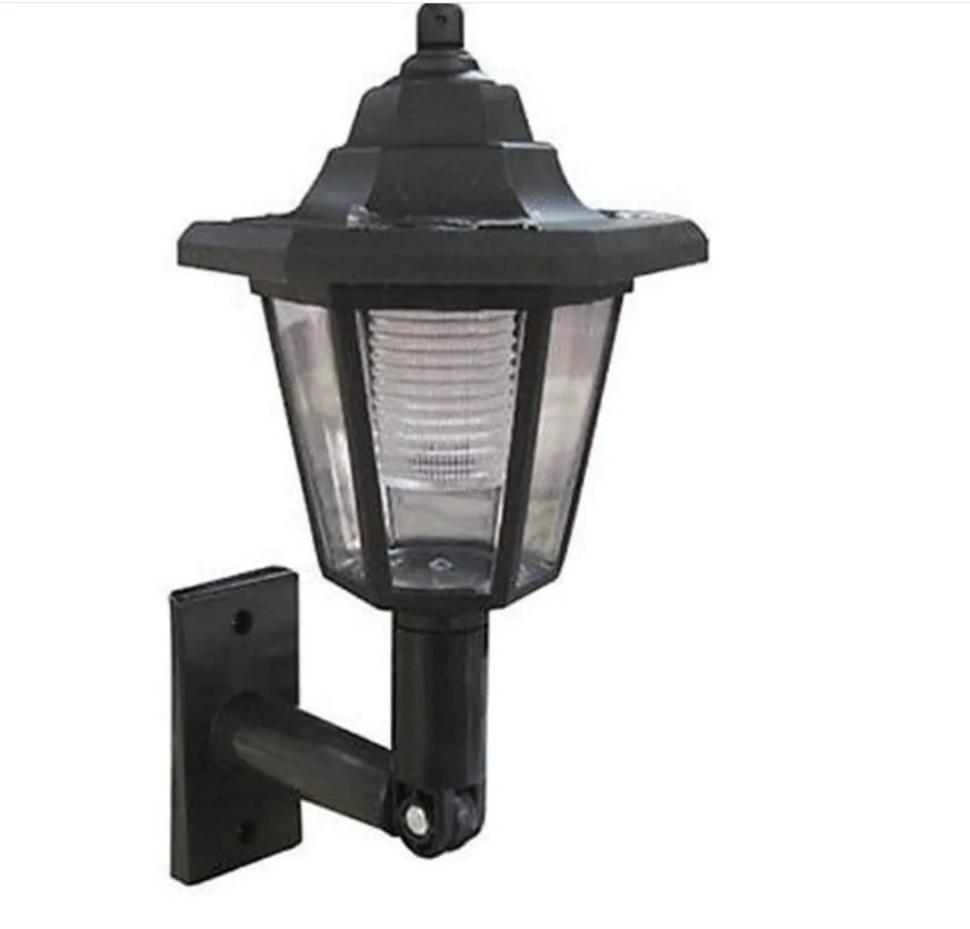 Black hexagonal solar-powered wall lamp for outdoor garden use, shown mounted on a fence