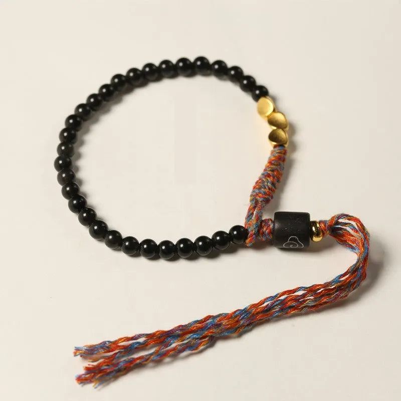 Slim obsidian-coloured hand-woven strap bracelet shown on a wrist.