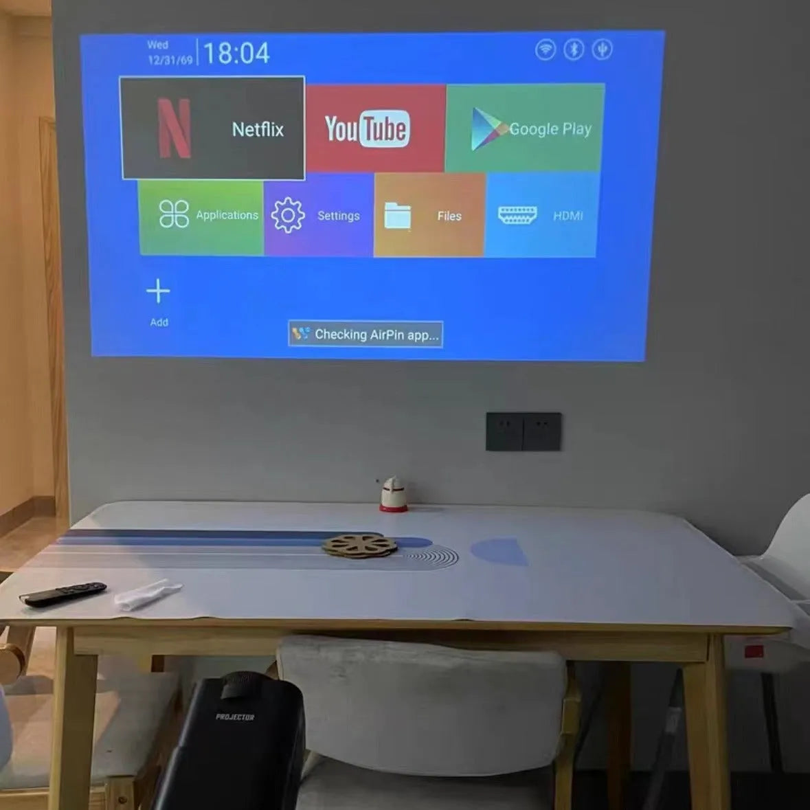 Black 720p wireless home projector on table with international power adaptors for gaming and media projection