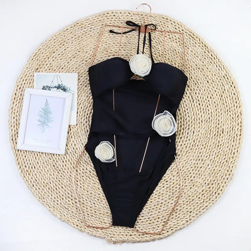 Women's black and blue striped one-piece swimsuit with 3D flower detailing.