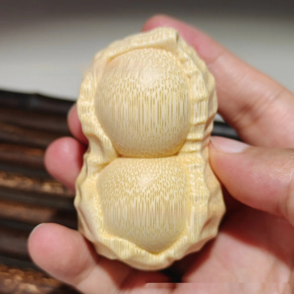 Solid natural bamboo carving peanut ornament on a neutral background