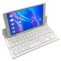 Black mini folding Bluetooth keyboard with bamboo pattern beside 7-inch tablet