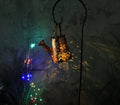 Solar-powered tapered butterfly pattern iron garden lamp emitting warm white light.