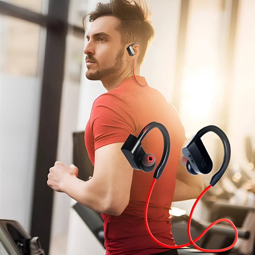 Black wireless neckband Bluetooth earphones with earbuds and a USB charging cable on a grey background.