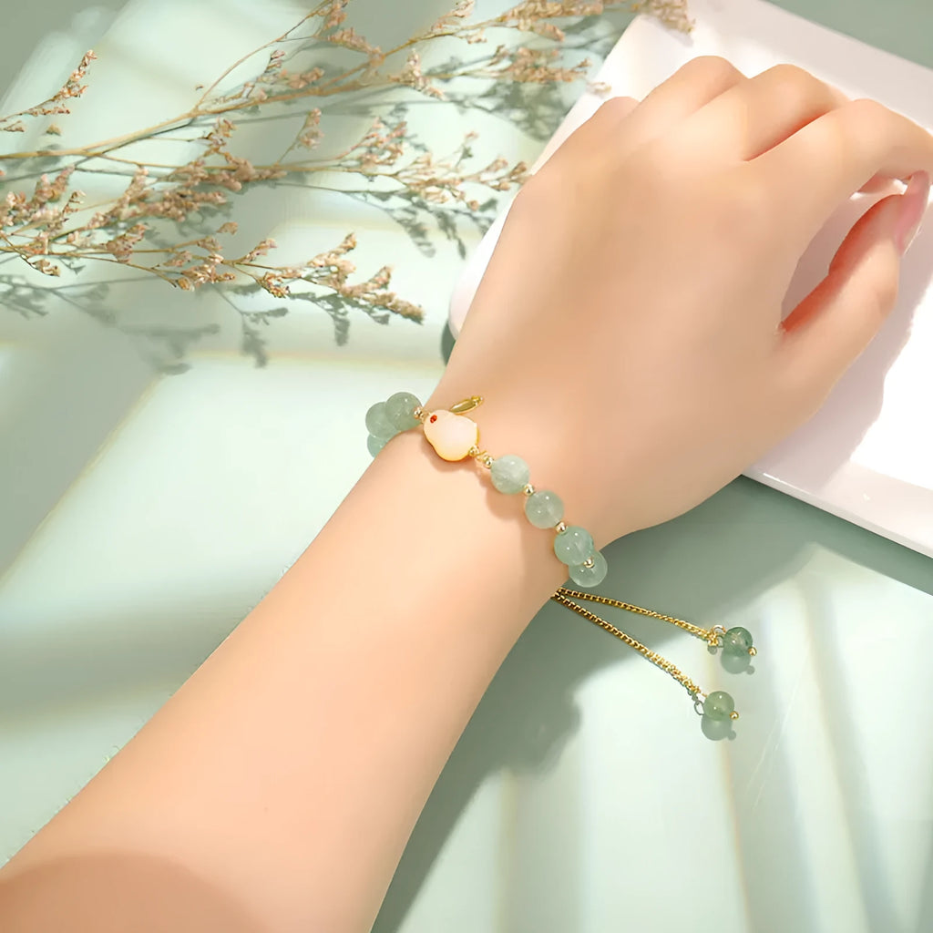 Rabbit charm bracelet with green aventurine and strawberry quartz stones on a gold or copper chain.