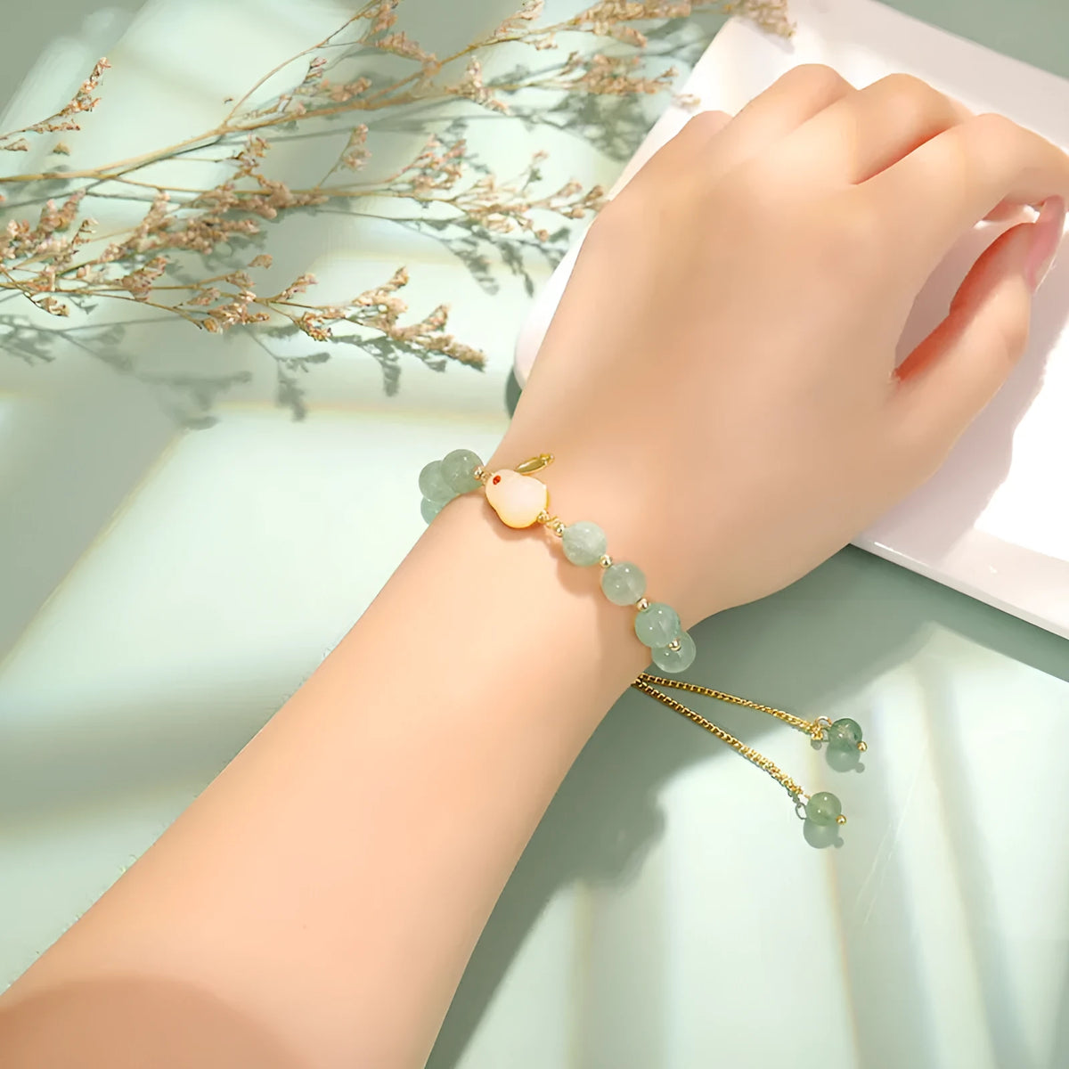 Rabbit charm bracelet with green aventurine and strawberry quartz stones on a gold or copper chain.