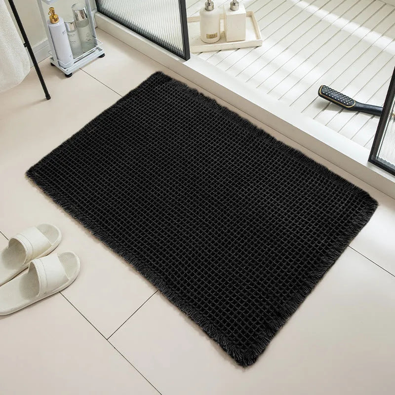 Square checkered pattern bath mat in beige colour on a bathroom floor.