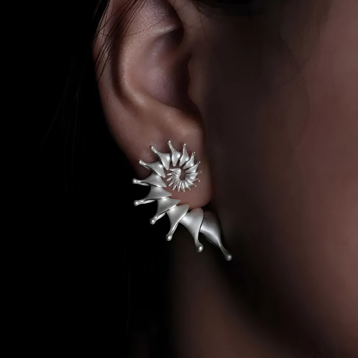 A pair of matte finish alloy conch stud earrings with a three-dimensional, irregular shape.