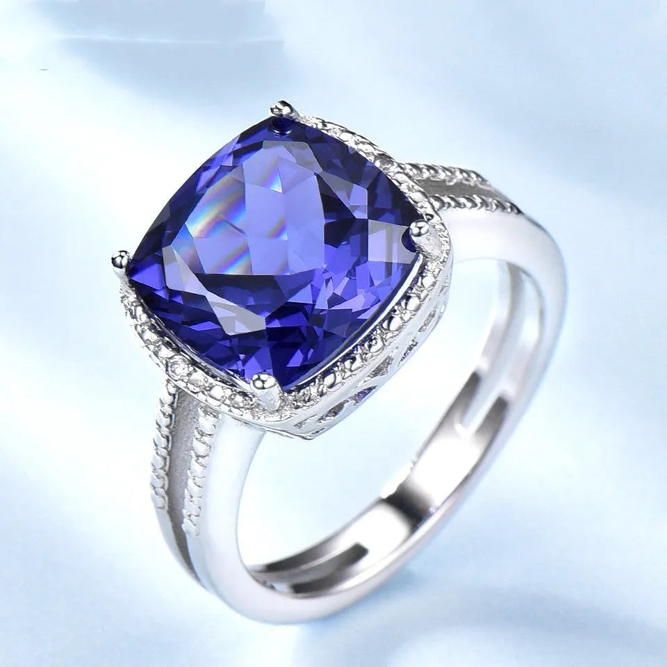 Blue tanzanite gemstone set in a sterling silver women's ring on a grey background.