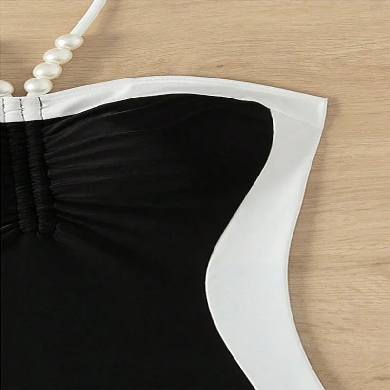Black and white women's one-piece swimsuit with pearl-decorated spaghetti straps for a slimming fit.