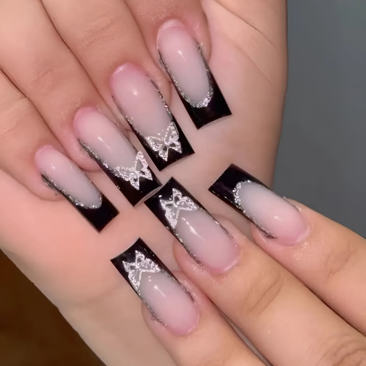 Black French style false nails with glittering butterfly patterns in medium length wearable armour design