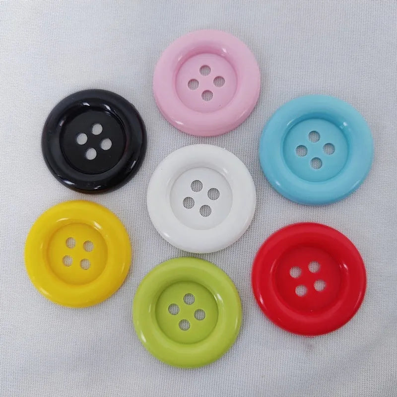 Oversized plastic nylon buttons in multiple colours with round edges and four stitching holes