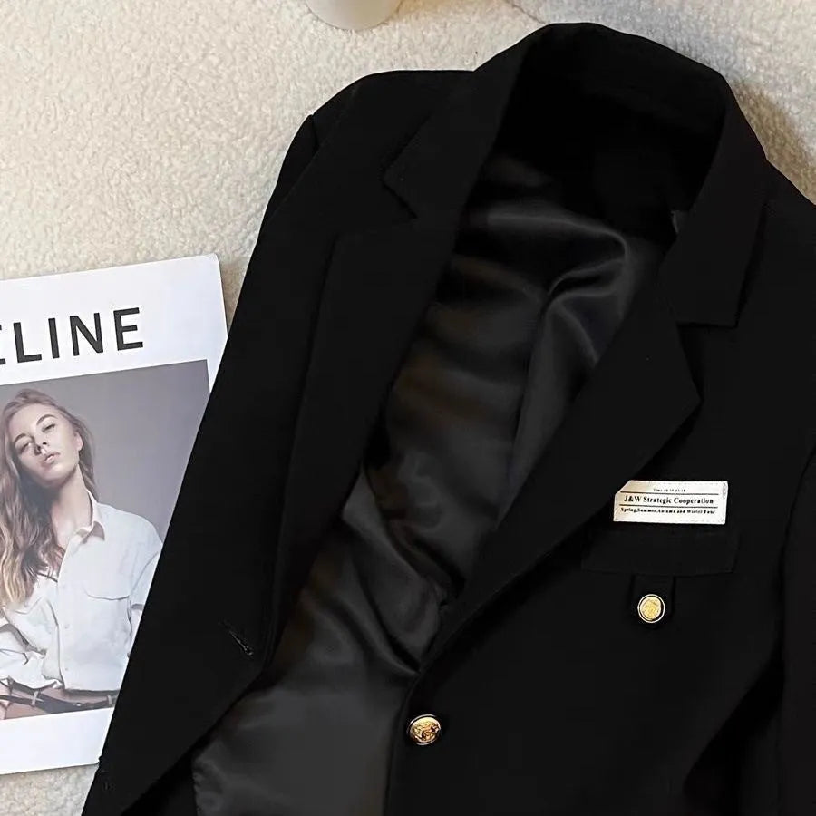 Women's black loose-fit suit coat with long sleeves and pockets on a hanger.