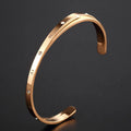 Open-ended stainless steel bracelet with electroplated finish and inlaid zircon stones.