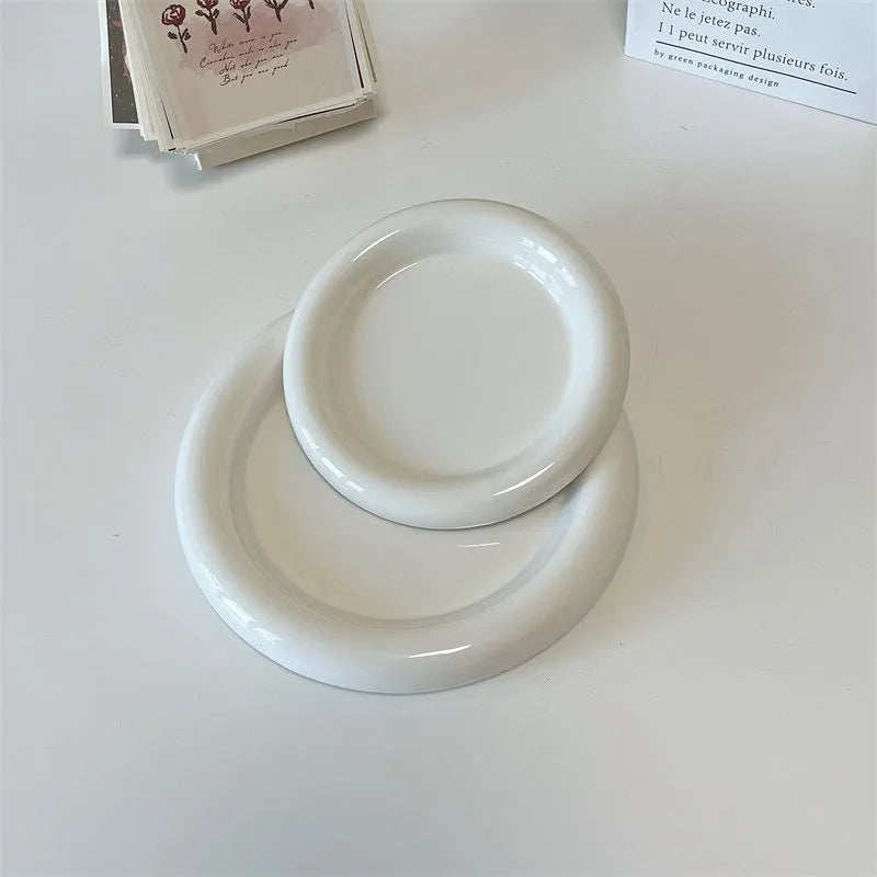 White porcelain plate with chubby toot design, showing bear or round doodle pattern, on a table.