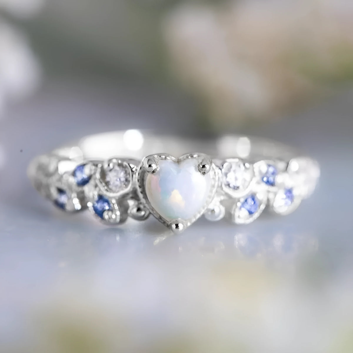 White alloy heart-shaped ring with floral opal ocean detail, shown on a size guide.