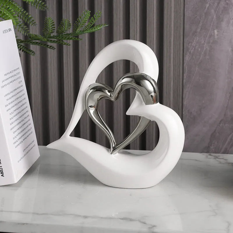 Modern geometric heart-shaped porcelain ornament in a metallic finish displayed on a cabinet.