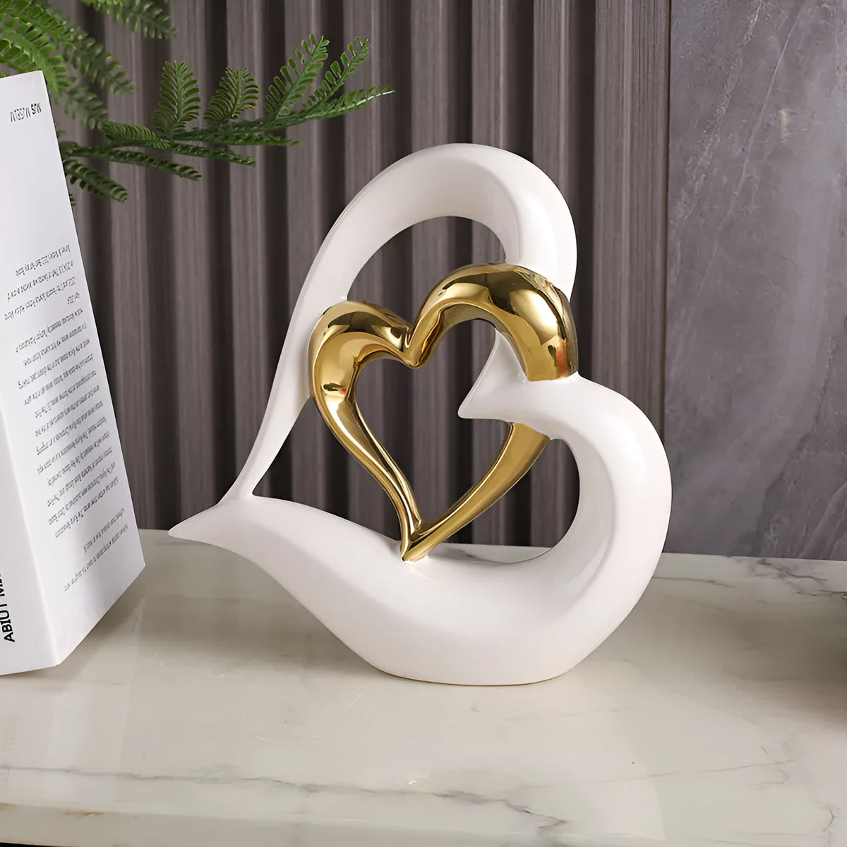 Modern geometric heart-shaped porcelain ornament in a metallic finish displayed on a cabinet.