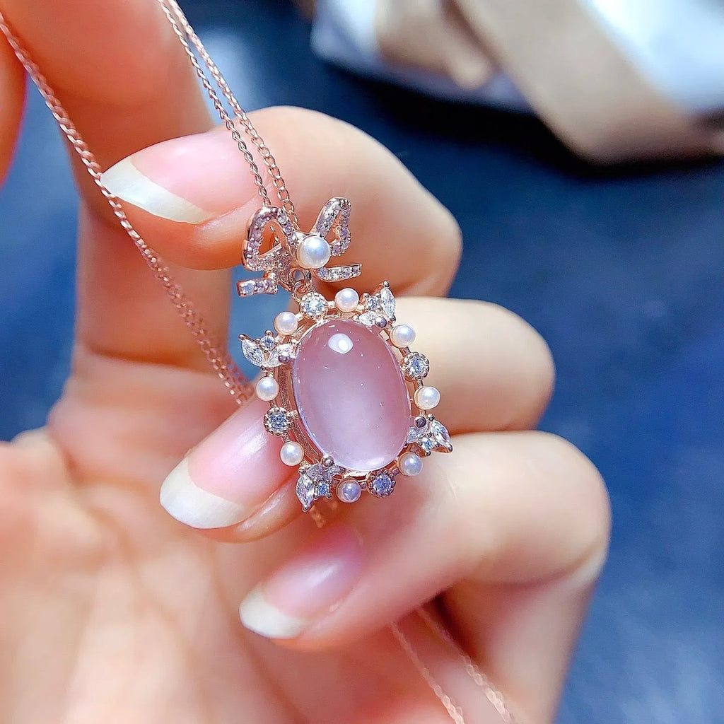 Close-up of a geometric rose gold plated silver pendant with a pink rose quartz stone on a chain.