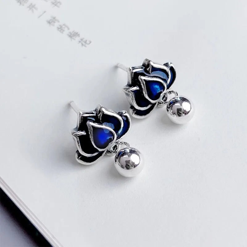 Blue lotus flower stud earrings with a seedpod tassel, showing front detail.