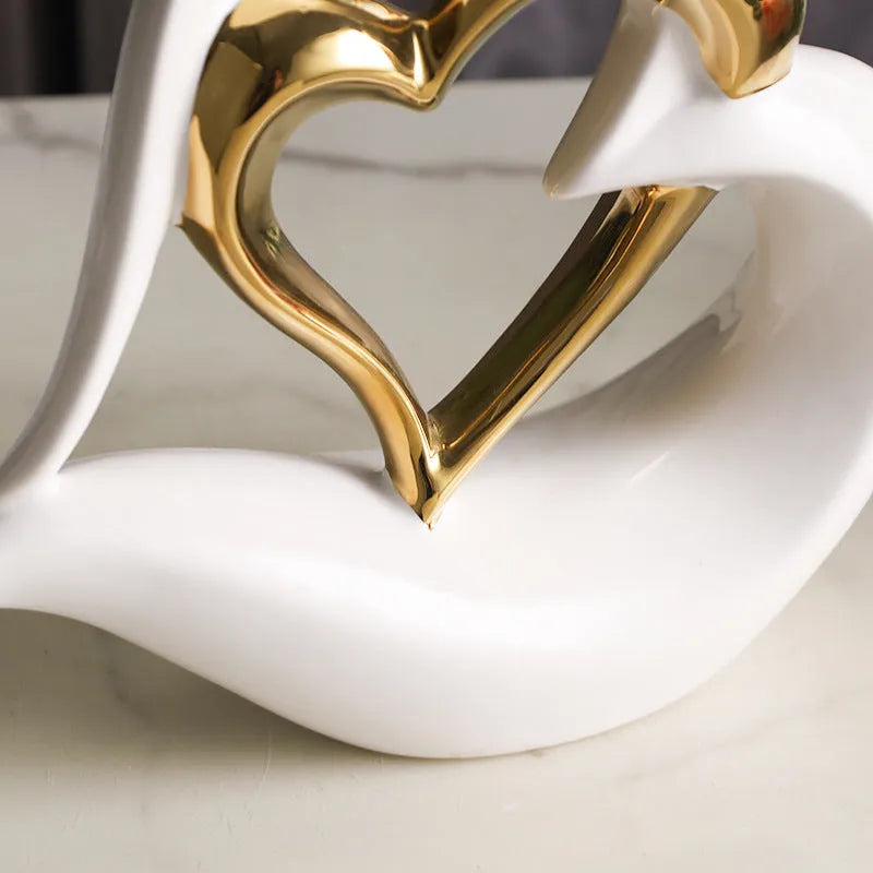 Modern geometric heart-shaped porcelain ornament in a metallic finish displayed on a cabinet.