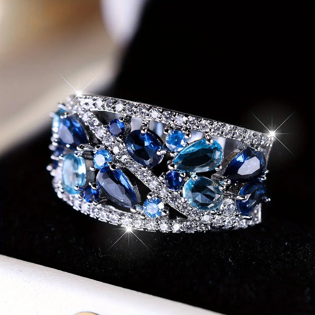 Women's round hollow fashion ring in gold or platinum plating with a blue or white cubic zirconia stone.