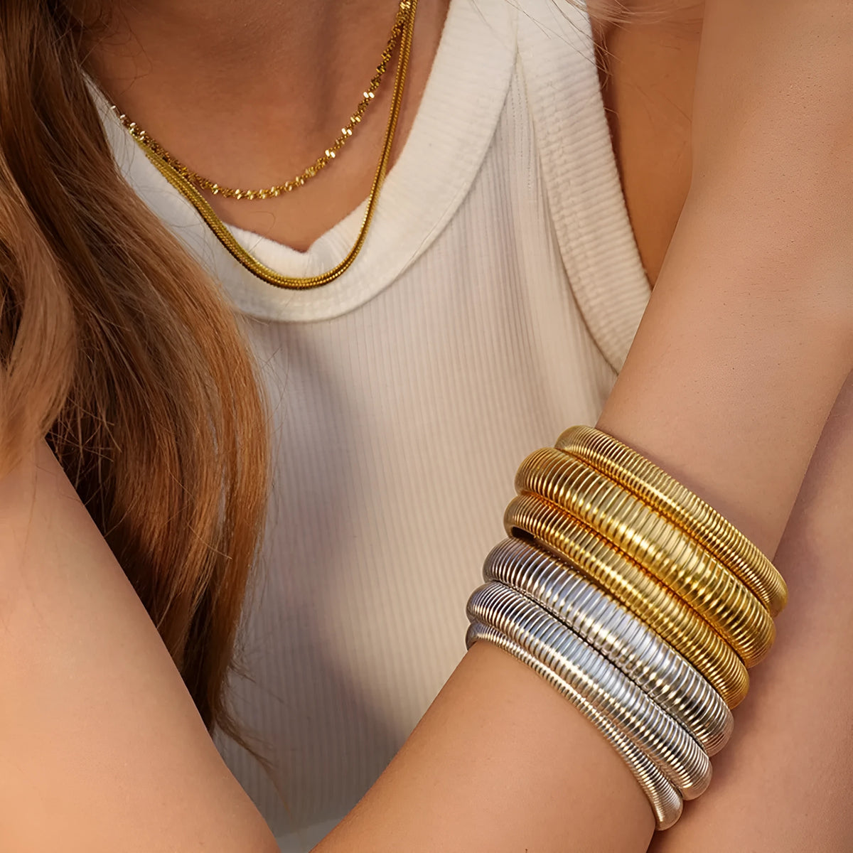 Gold titanium steel women's bracelet with vertical stripes and elastic ring design on a wrist.
