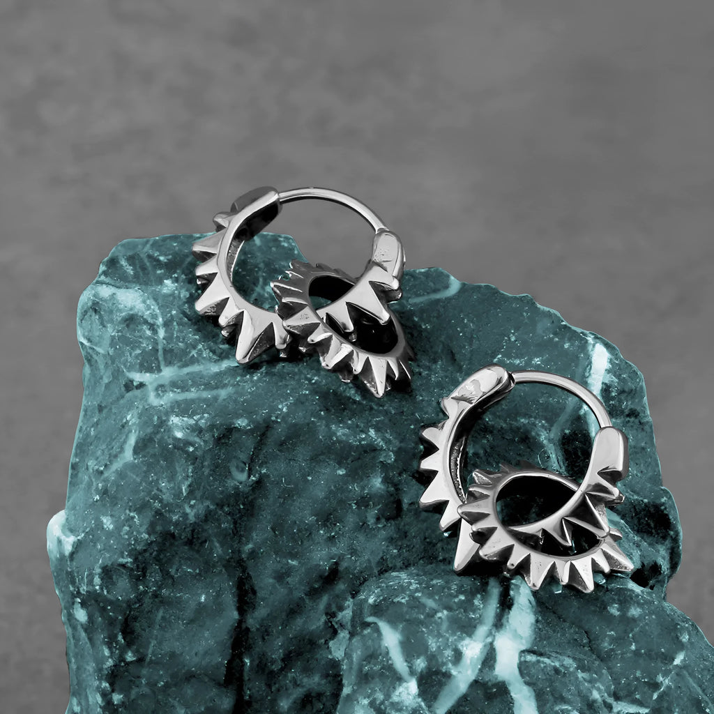 A pair of simple, polished stainless steel round ring hoop earrings on a steel colour background.
