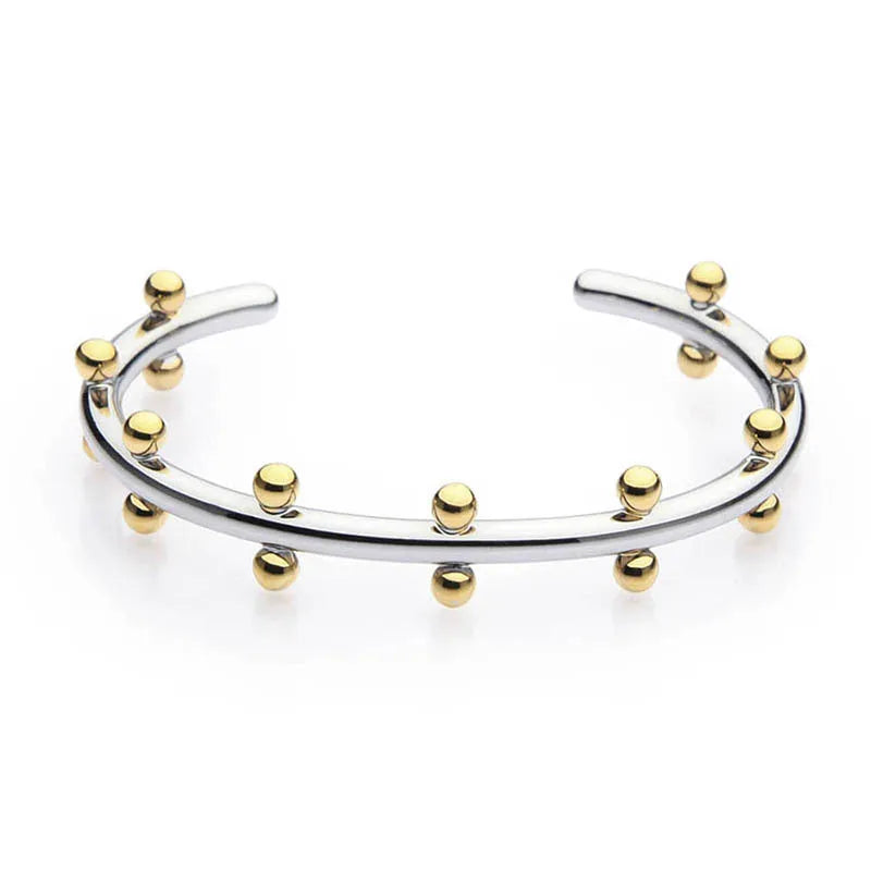 C-shaped stainless steel alloy bracelet with textured rivet-shaped beads on a wrist.