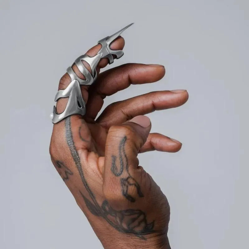 Silver coloured alloy punk armour finger stall ring on a hand.