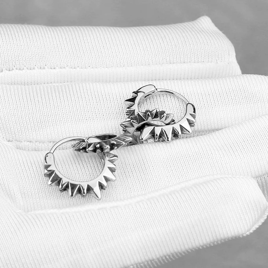 A pair of simple, polished stainless steel round ring hoop earrings on a steel colour background.