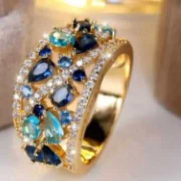 Women's round hollow fashion ring in gold or platinum plating with a blue or white cubic zirconia stone.
